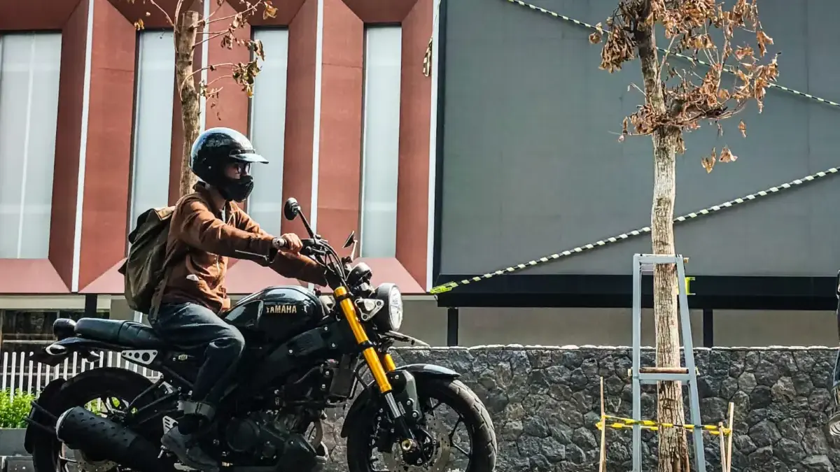 Warga menggunakan sepeda motor melintas di samping pohon yang mengering saat musim kemarau di Jalan LL.R.E. Ma