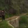 Dua warga bergotong royong menandu seorang pasien melewati jalan rusak dan terjal di Kampung Cicapeu, Desa Kid