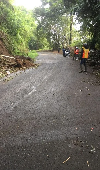 EVAKUASI: Petugas mengerahkan satu unit mobil pemadam kebakaran untuk menyemprotkan sisa material longsor yang masih menggantung di tebing. DOK PASUNDAN EKSPRES