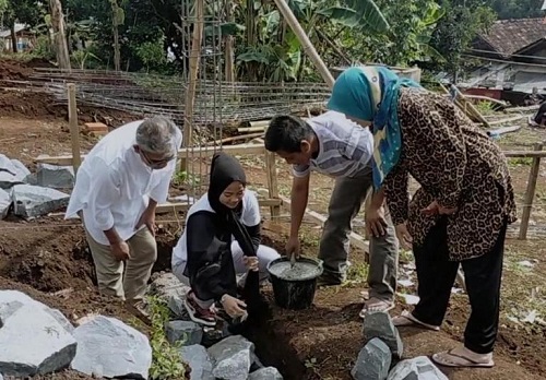 PELETAKAN BATU PERTAMA: Atlet Angkat Besi asal Kabupaten Bandung, Windy Cantika, saat meletakan sebuah batu dan adukan semen pertama pada bangunan pondasi bangunan masjid, Minggu (30/1). JABAR EKSPRES