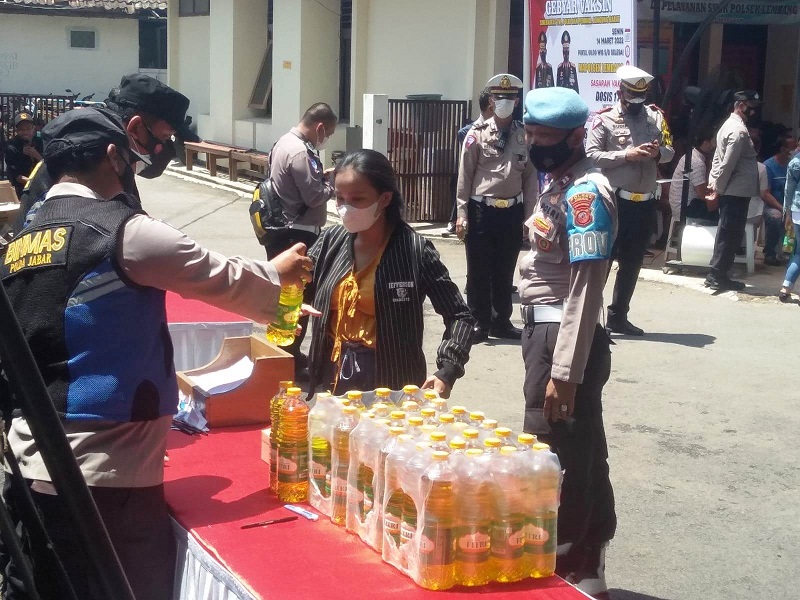 VAKSINASI: Petugas kepolisian memberikan minyak goreng kemasan kepada warga yang sudah mengikuti vaksinasi Covid-19 di Mapolsek Lembang, Senin (14/3). EKO SETIONO/PASUNDAN EKSPRES