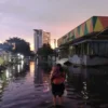 BANJIR: Seorang ibu menggendong sang anak di tengah genangan banjir yang melanda di wilayah Pasar Induk Gedebage,