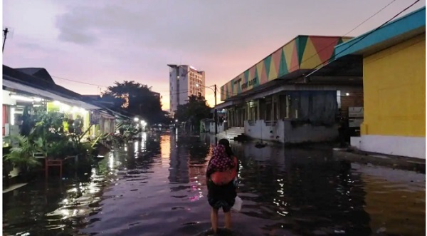 BANJIR: Seorang ibu menggendong sang anak di tengah genangan banjir yang melanda di wilayah Pasar Induk Gedebage,