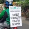 KONVOI : Salah seorang anggota Khilafatul Muslimin membagikan selebaran kepada pengendara pada aksi konvoi di sekitar jalan Parongpong dan Cisarua wilayah Bandung Barat, Minggu (29/5). Ilustrasi