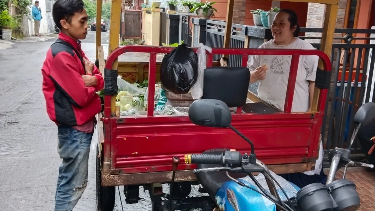 Ajang salah seorang pedagang sayuran keliling sedang melayani pembeli, Selasa (28/03) pagi.