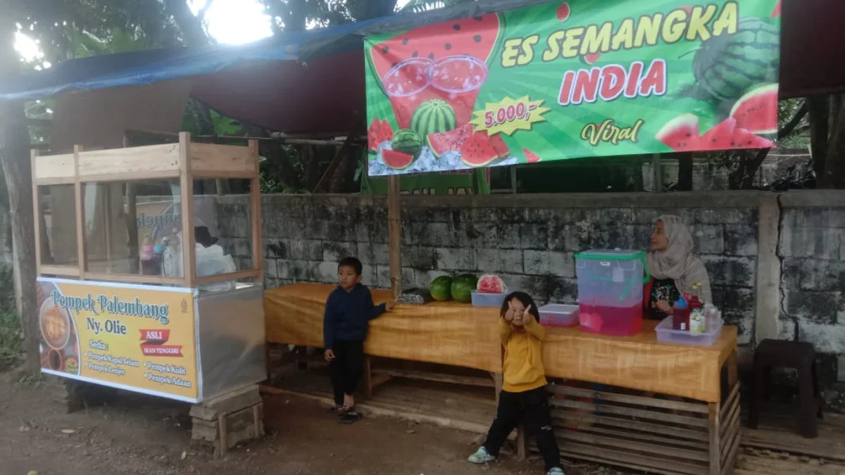 Olie, ditemani kedua anaknya saat sedang berjualan di Jalan Gatot Subroto, Perumahan BCI, Garut, Kamis 14 Mare