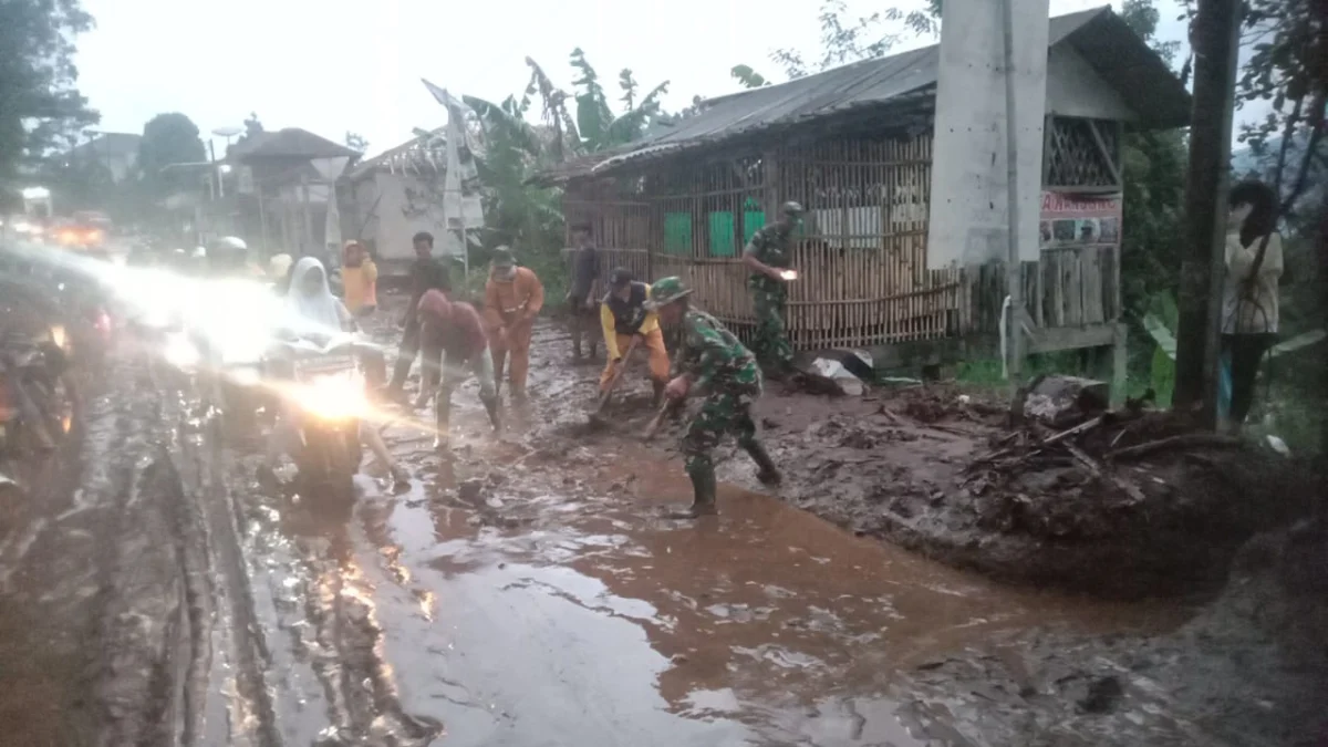 petugas TNI dan Polisi berusaha membersihkan lumpur di jalan raya