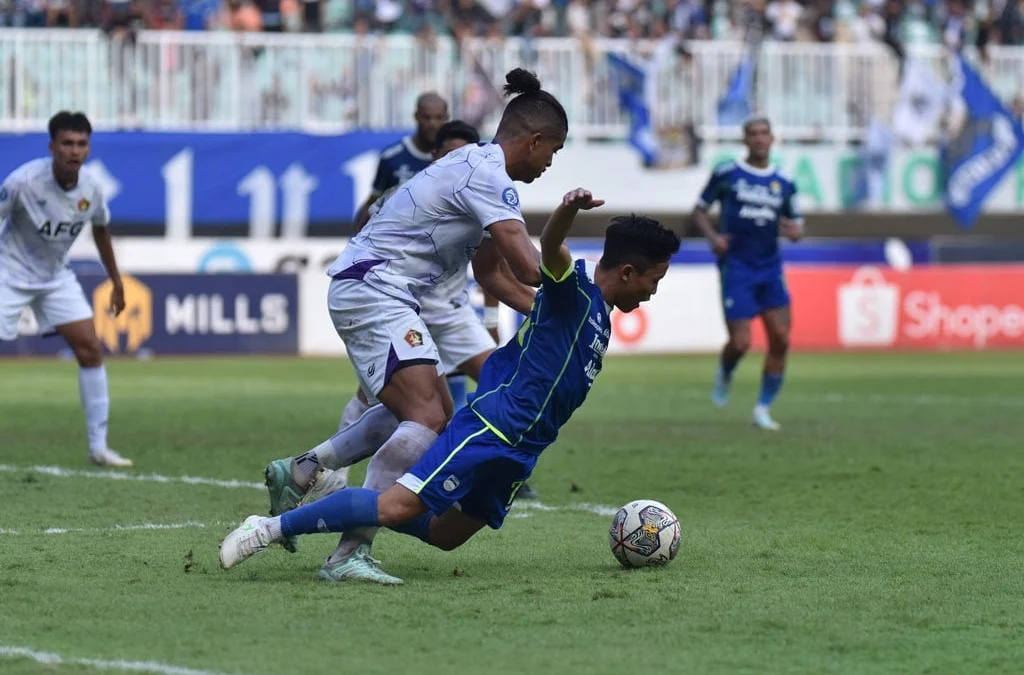 Gelandang Persib Bandung (baju bru) Arsan Makarim Terjatuh di Laga kontra Persik, Rabu (8/3). Sumber Foto: Situs Resmi Persib/Amandeep Rahimah