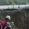 Petugas melintas di sekitar jalan tol yang amblas di ruas tol Bocimi KM 64