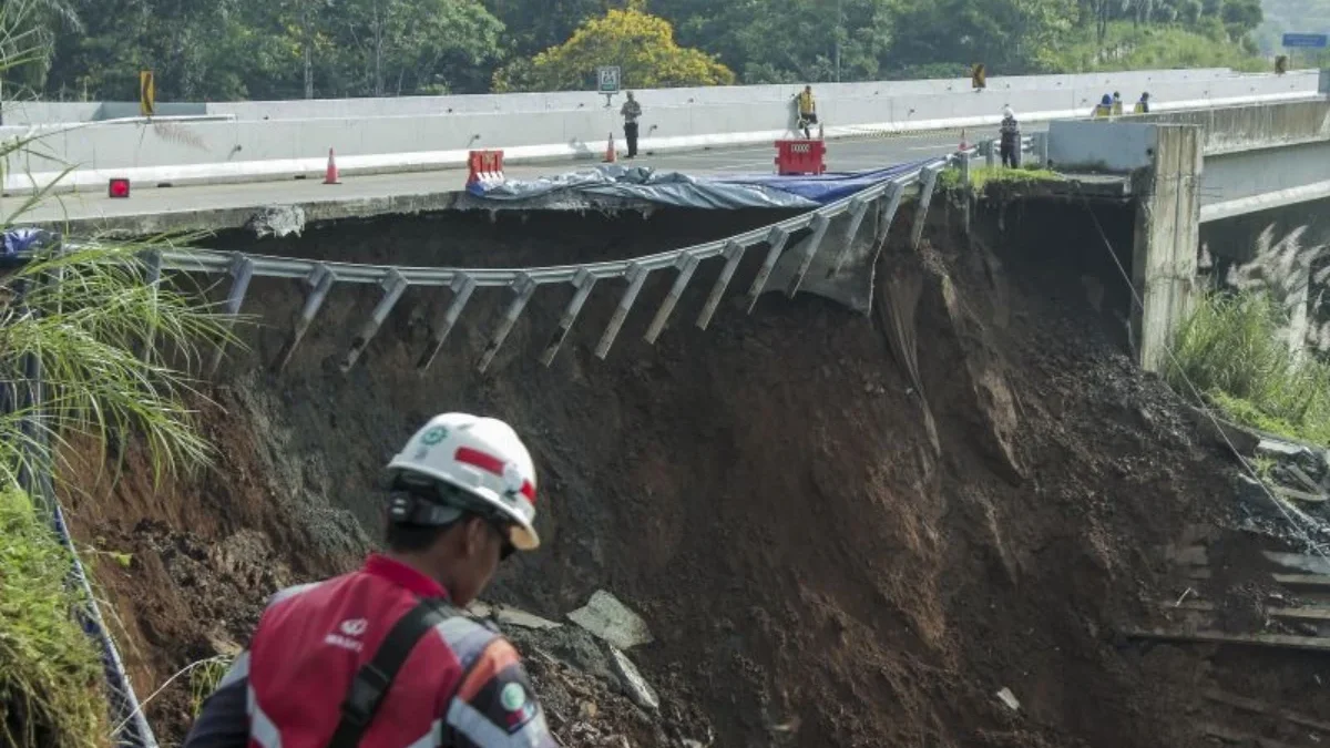 Petugas melintas di sekitar jalan tol yang amblas di ruas tol Bocimi KM 64