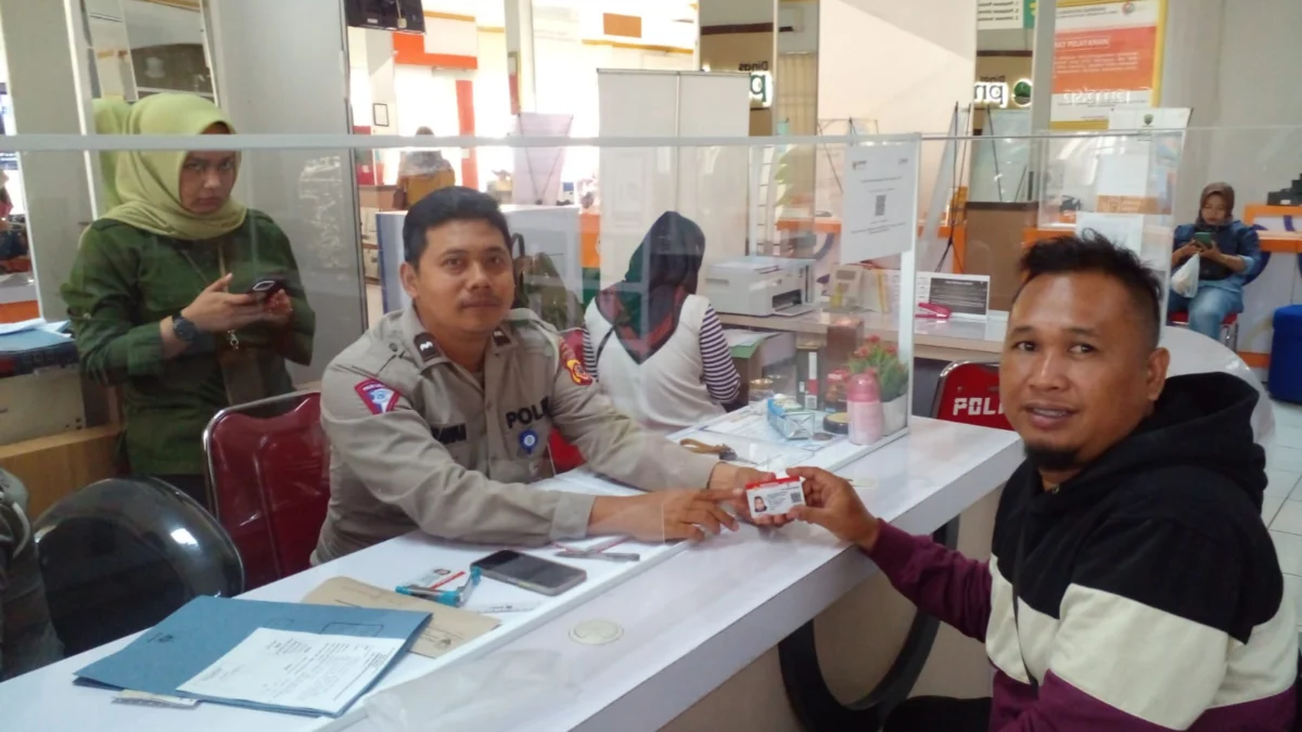 RAMAH: Staff SIM di Gedung MPP, Aipda Ade Irawan SE., saat menyerahkan SIM baru kepada salah satu warga yang memperpanjang SIM di loket G Gedung MPP Sumedang. . (Foto Ahmad Sofa)