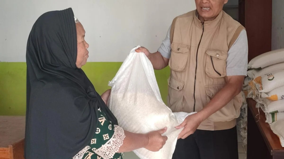 SIMBOLIS: Lurah Situ saat memberikan bantuan beras 10 Kg, kepada salah seorang warganya, yang bersumber dari bantuan Badan Ketahanan Pangan Nasional dan Bulog, di Desa Situ, baru-baru ini. Istimewa