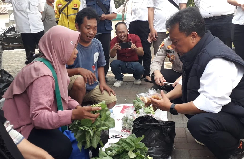 ATEP BIMO AS/SUMEKS BERBINCANG: Pj Bupati Sumedang Herman Suryatman saat berbincang dengan tukang sayur, dalam Kegiatan Pasar Murah di Alun-alun Tegalkalong, kemarin.