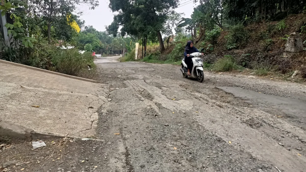 ATEP BIMO AS/SUMEKS WASWAS: Seorang warga saat melintasi jalan rusak di wilayah Desa Cacaban Kecamatan Conggeang, kemarin.