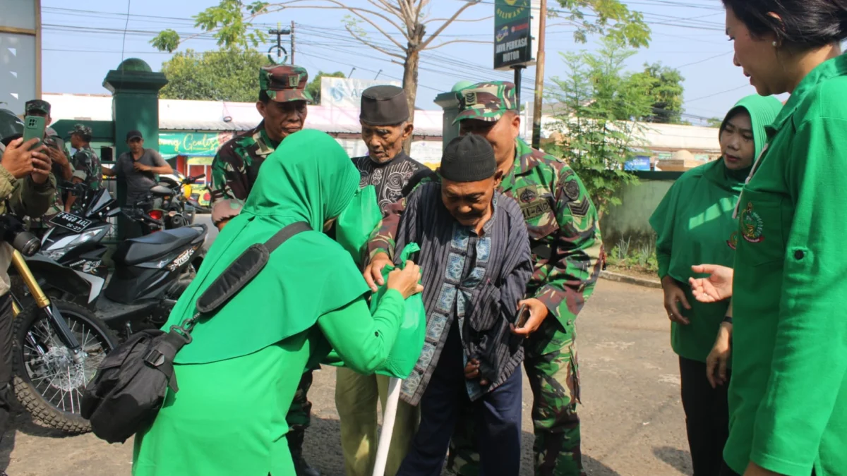 BANTU: Dandim 0610/Sumedang Letkol Kav Christian Gordon Rambu M.Si (Han) membantu orang tua berdiri untuk menerima bantuan sembako, baru-baru ini.