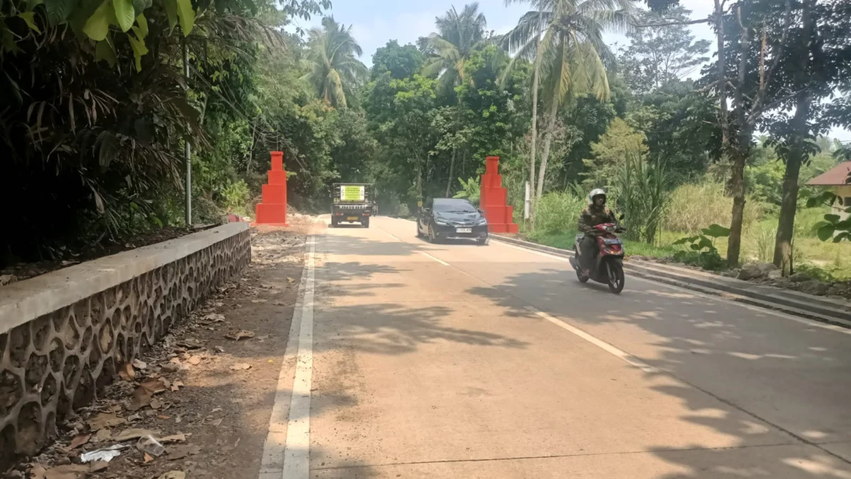 KECIL: Pengendara tengah melintasi tugu batas Desa Cibeureuyeuh dan Narimbang di Kecamatan Conggeang, yang dinilai berukuran sangat kecil dan disayangkan warga, baru-baru ini.