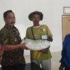 PEDULI: Kepala Desa Jatihurip, Tata saat memberikan bantuan beras 10 Kg kepada salah seorang warganya, baru - baru ini.