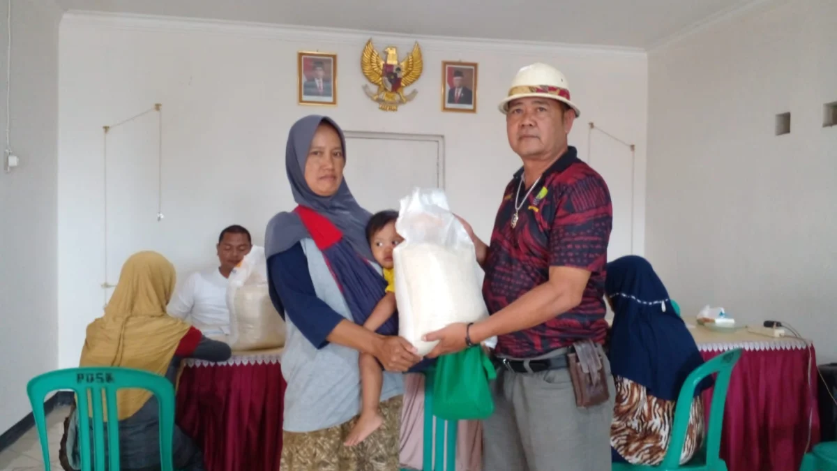 SIMBOLIS: Simbolis penyerahan beras 10 Kg oleh Kepala Desa Padasuka, Gamis kepada salah seorang warga yang merupakan KPM di Desa Padasuka, baru-baru ini.