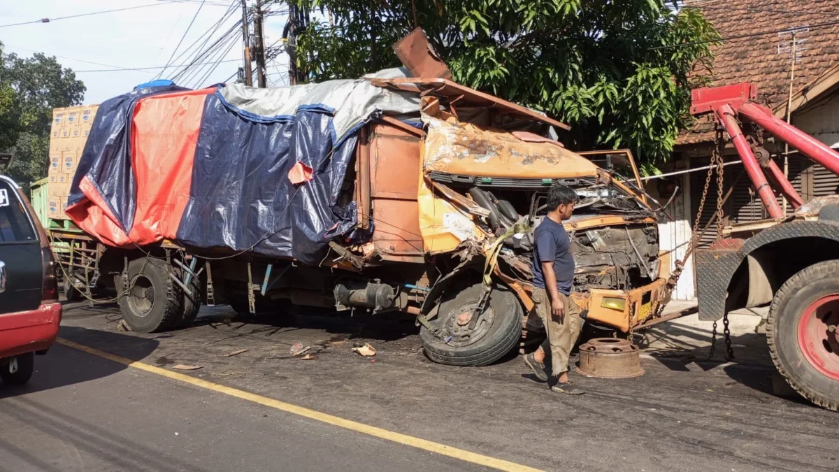 RIGSEK: Salah seorang warga sedang mengamati bangkai truk pengangkut air mineral, setelah terlibat tabrakan di