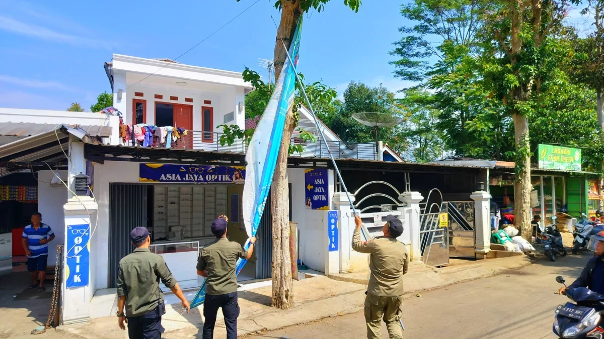 PENERTIBAN: Anggota Satpol PP Sumedang menertibkan spanduk yang melangar aturan di sepanjang jalan Simpang – P