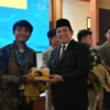 TUTUP: Pj Bupati Sumedang Yudia Ramli saat memberikan produk UMKM ke salah satu Mahasiswa di Acara Penutupan P