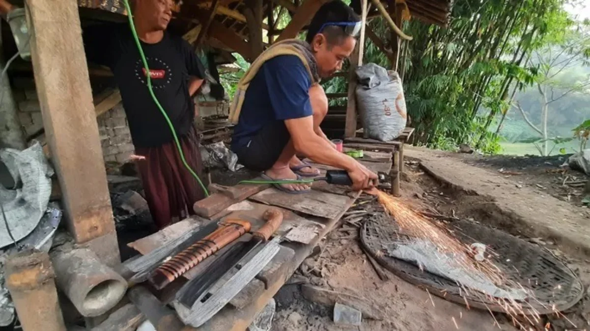 BUAT: Salah seorang warga Cimungkal Wado saat membuat sebuah golok, belum lama ini.