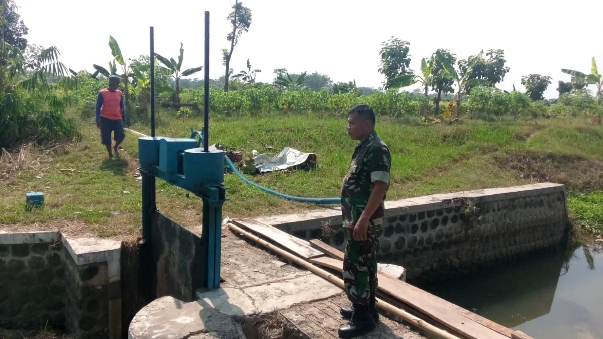 MENGERING: Seorang Petani dan Aparat TNI mengecek saluran Irigasi di Ujungjaya yang mengering akibat Bendungan