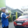 ATUR: Salah seorang petugas sedang mengatur kendaraan yang hendak parkir di halaman RSUD Sumedang, kemarin.