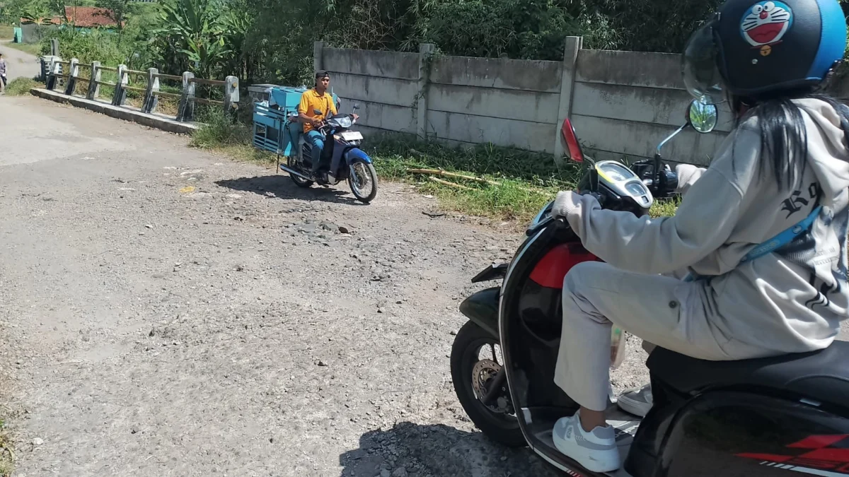 MEMPRIHATINKAN: Sejumlah warga saat melintas di ruas jalan yang rusak di Desa Mekarjaya Kecamatan Sumedang Uta