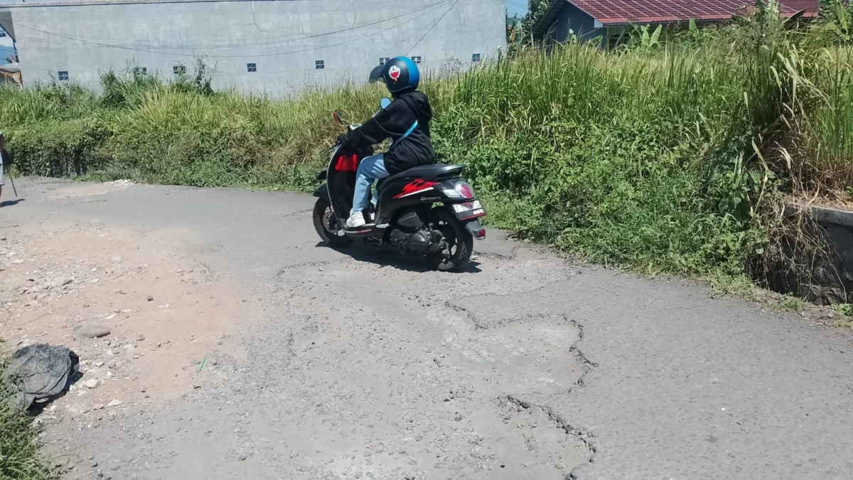 LEWATI: Salah satu warga saat melintasi jalanan yang rusak di Babakan Kelurahan Situ Kecamatan Sumedang Utara,