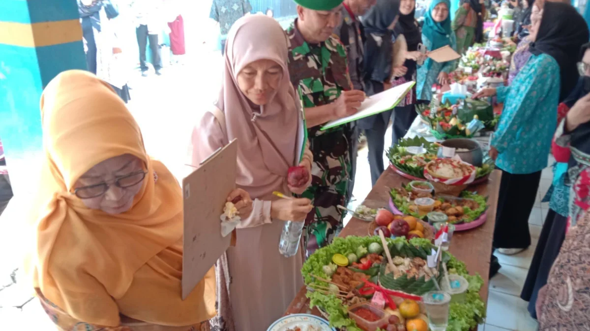 BERI NILAI: Danramil 1001/Sumedang Utara, Kapten Caj Yayat saat menilai perlombaan nasi tumpeng di Desa Margam