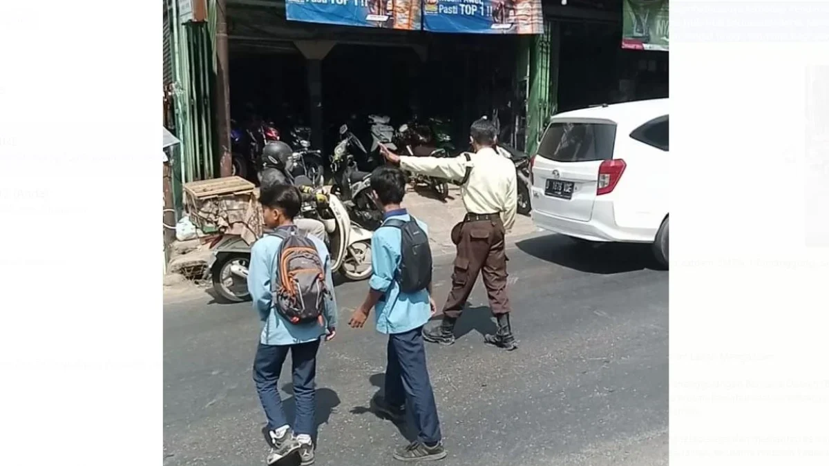 JAGA KESELAMATAN: Soni Julianto satpam SMPN 1 Cimanggung, saat membantu siswa menyeberang jalan, Senin (2/9).