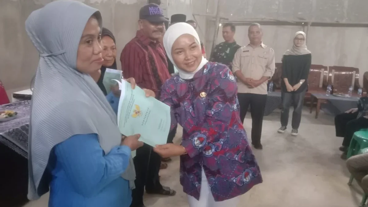 BERIKAN: Kepala Desa Pasirnanjung, Susi Herawati secara simbolis saat menyerahkan sertifikat tanah program PTS