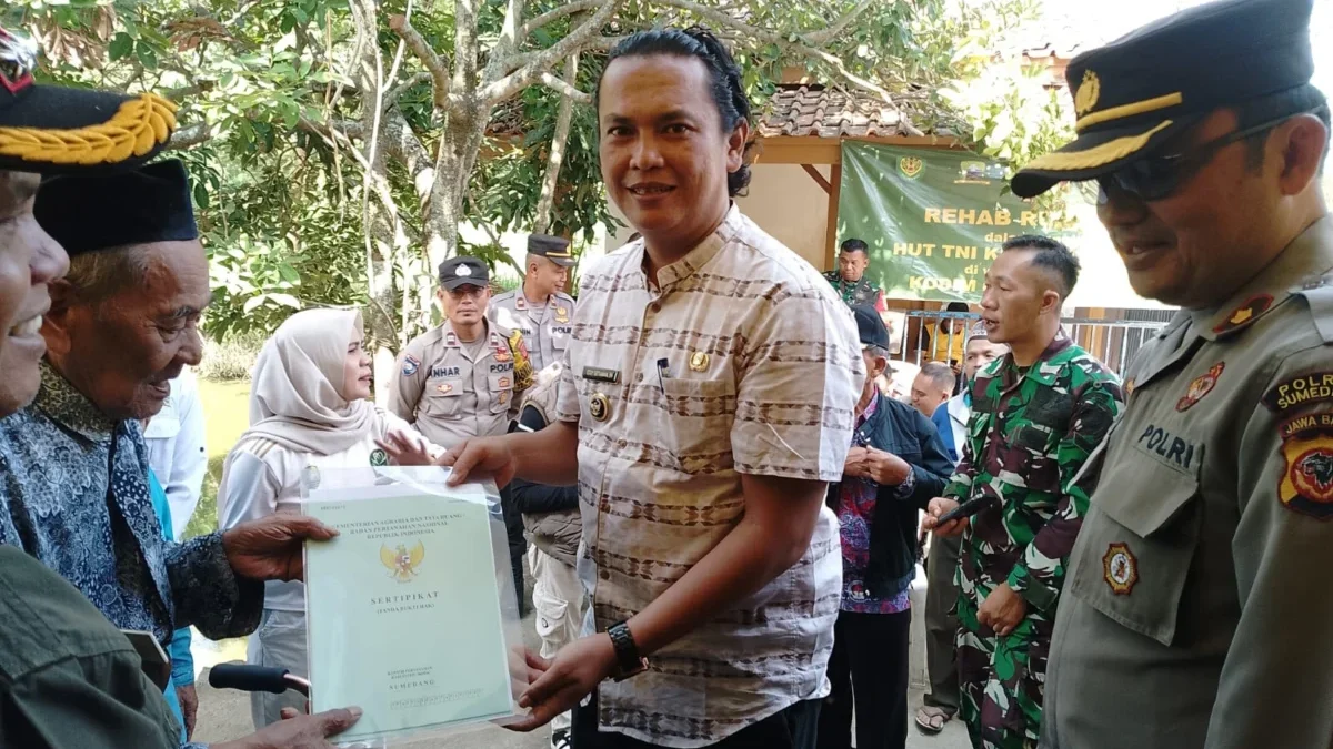 BERI BANTUAN: Kepala Desa Sindanggalih Eddy Setiawan saat memberikan sertifikat kepada salah satu warganya, ba