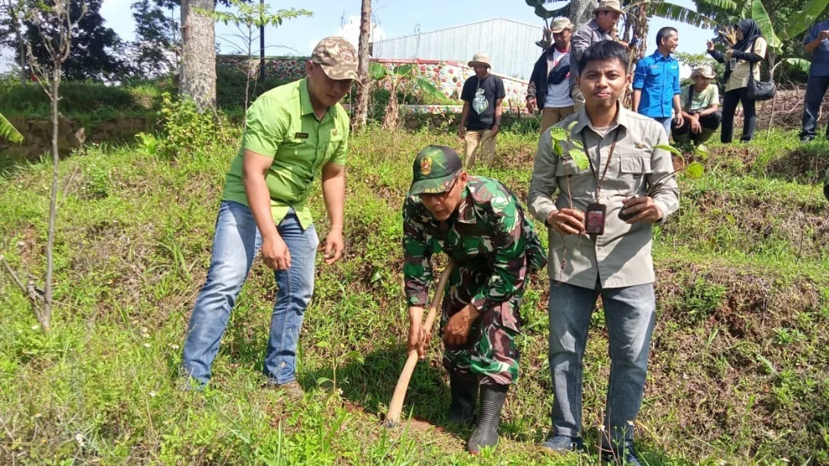 PENGHIJAUAN: Danramil 1014/Cimanggung Lettu Inf Nanang Koswara (tengah) saat menanam pohon di Desa Pasirnanjun