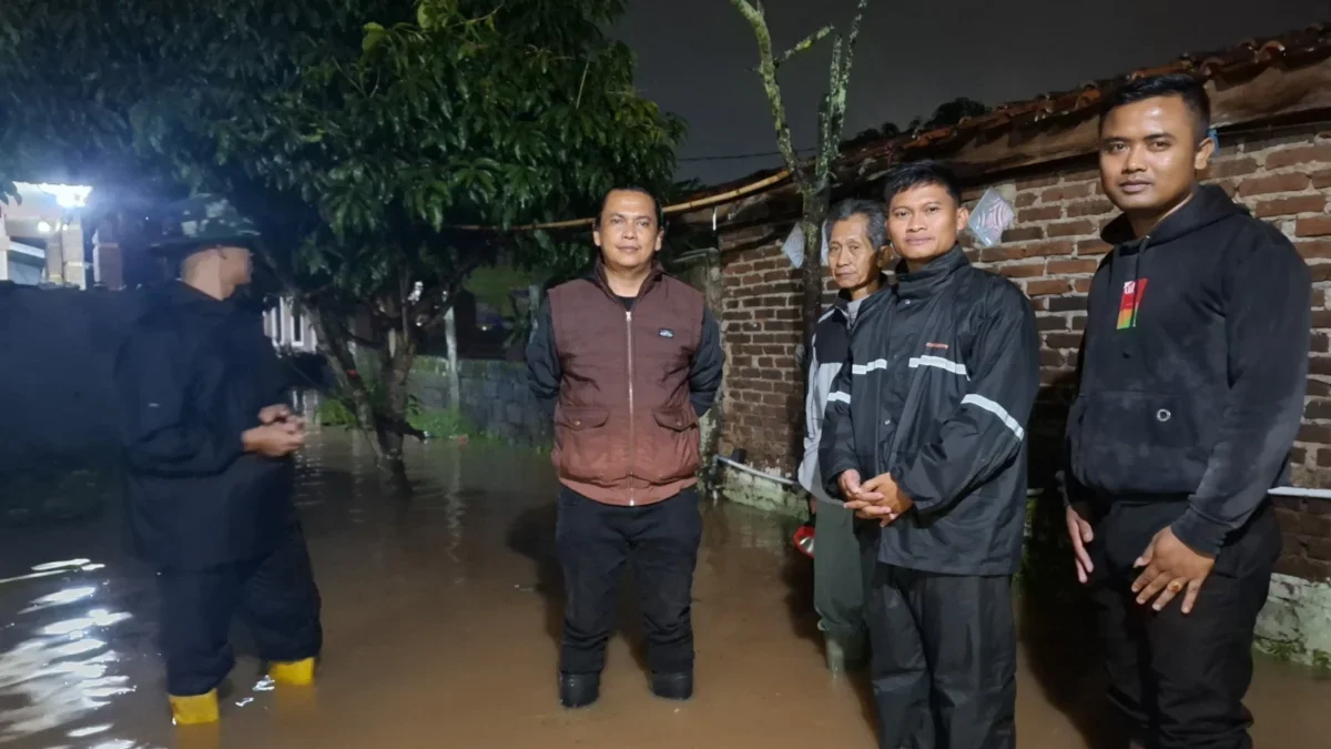 TANGANI: Kepala Desa Sindanggalih Eddy Setiawan saat meninjau titik lokasi banjir, Minggu (1/12) malam.