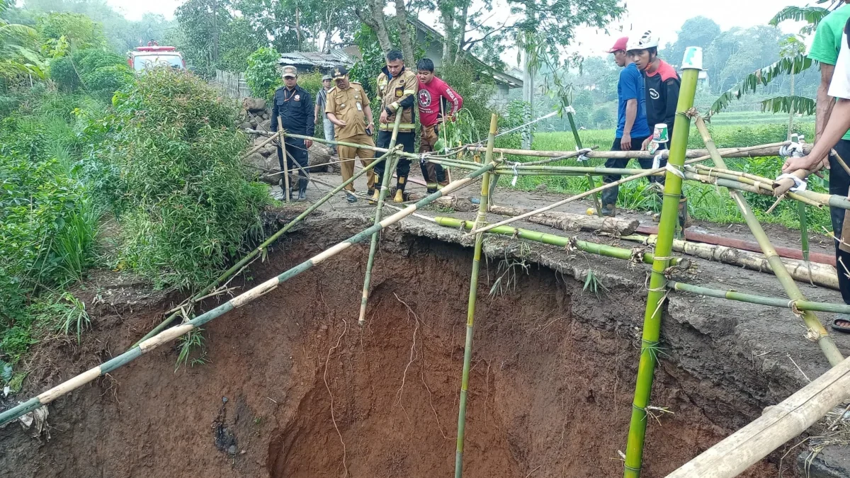 AMBRUK: Sejumlah aparat saat meninjau tanah amblas di Desa Cilayung Kecamatan Jatinangor, kemarin.