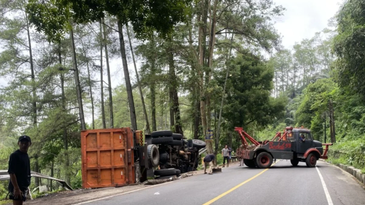 LAKA LANTAS: Sejumlah petugas saat mengevakuasi truk terguling di Jalan Cadas Pangeran, kemarin.