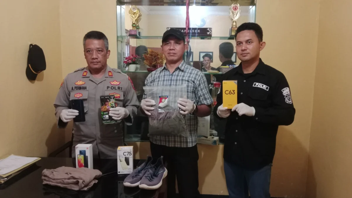 AMANKAN: Petugas kepolisian Polsek Situraja saat menunjukkan barang bukti pencurian berupa handphone di Polsek