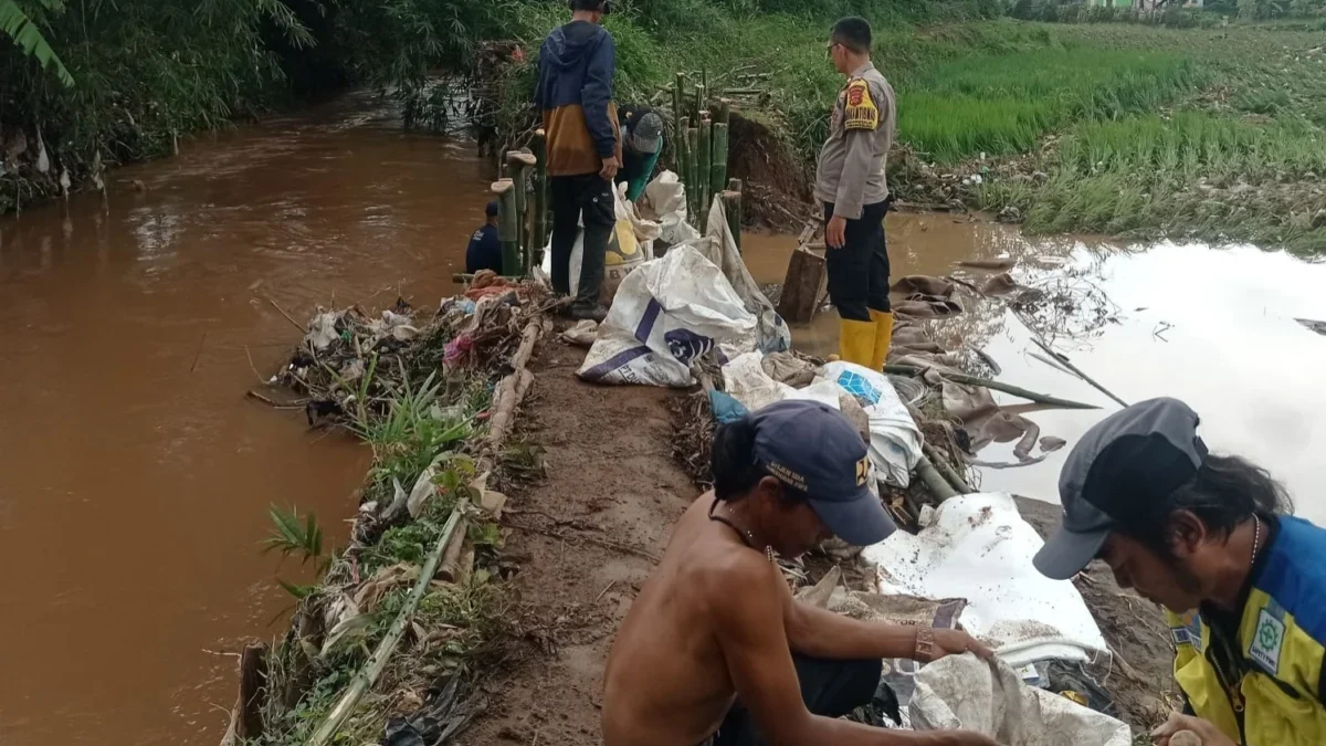 MELUAP: Sejumlah warga saat berupaya memperbaiki tanggul yang jebol di Kecamatan Cimanggung, baru-baru ini.