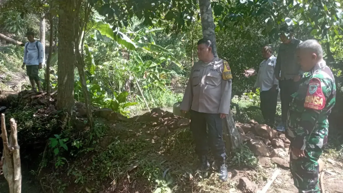 PASTIKAN: Bhabinkamtibmas Desa Sukagalih, Aiptu Agus Setiawan, saat monitoring pelaksanaan peningkatan saluran