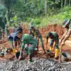 BERSINERGI: Sejumlah personil Satgas TMMD saat bergotong royong melakukan pengecoran jalan di Desa Pamulihan K