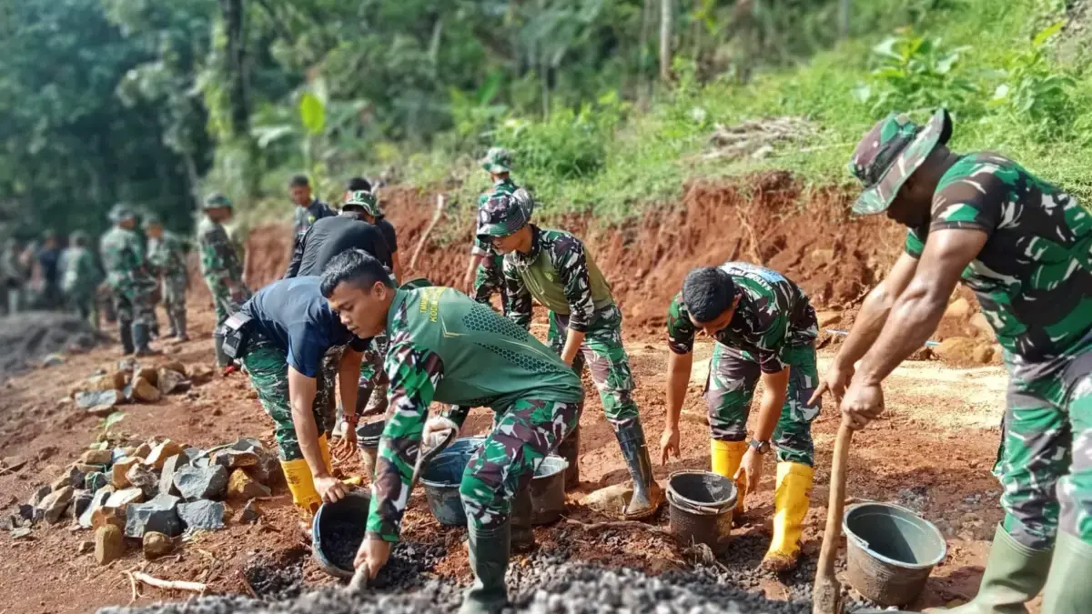 BERSINERGI: Sejumlah personil Satgas TMMD saat bergotong royong melakukan pengecoran jalan di Desa Pamulihan K