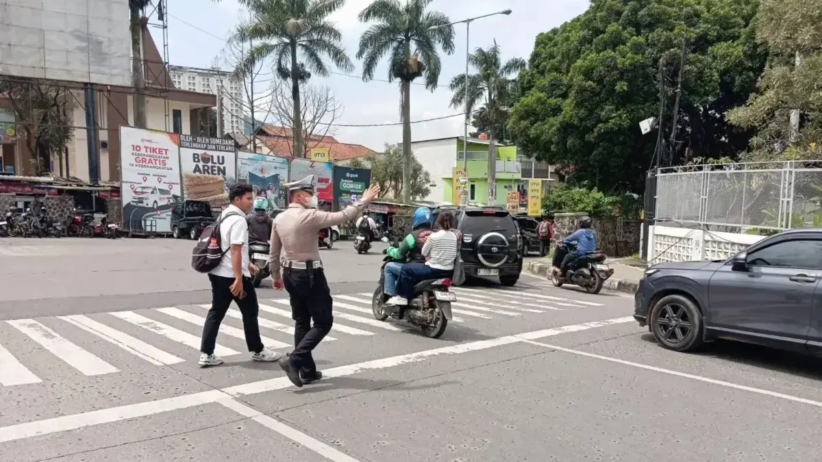 BANTU WARGA: Petugas Polsek Jatinangor, saat melakukan pengaturan lalu lintas serta membantu warga menyebrang