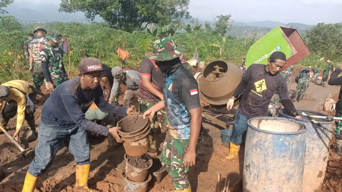 GOTONG ROYONG: Personil Satgas TMMD bersama warga saat melaksanakan pengecoran jalan di Desa Pamulihan Kecamat