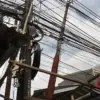 Ilustrasi - Kabel utilitas yang menjuntai dan saling silang di kawasan perkotaan, mencerminkan lemahnya penata