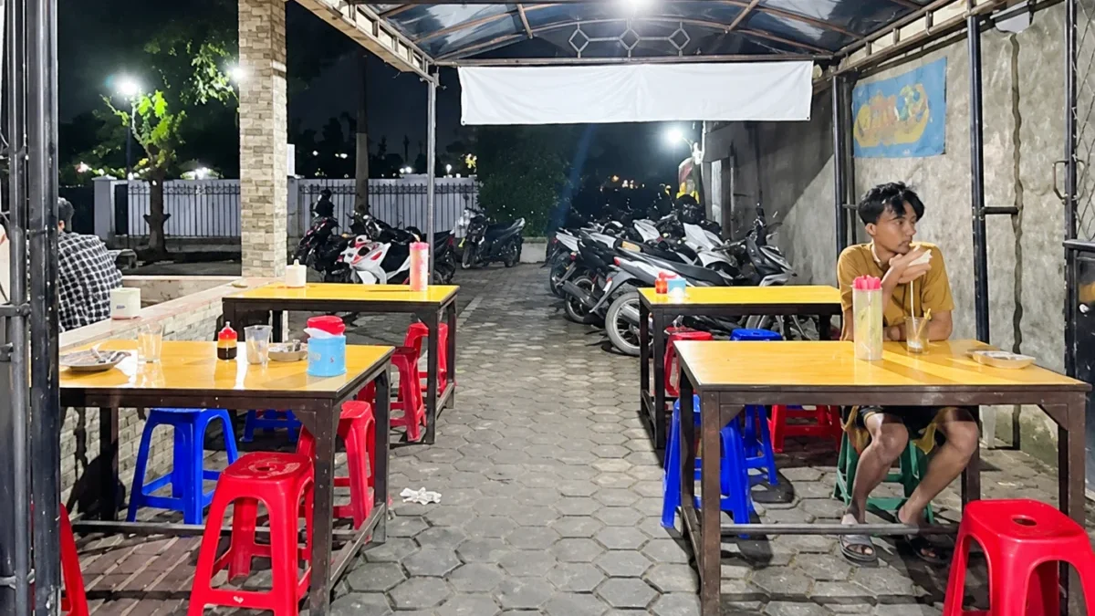 5 Warkop 24 Jam di Jatinangor untuk Mahasiswa, Harga Mulai Rp 2.000 Suasana warung kopi pada malam hari dengan meja dan kursi untuk pengunjung.